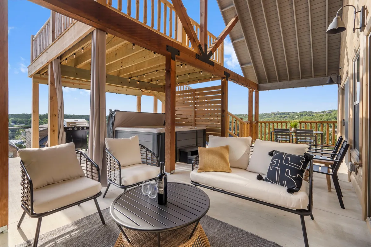 An exterior shot of an outdoor hot tub set on a deck with inviting seating and sweeping views of the surrounding landscape. The scene suggests a peaceful retreat ideal for relaxing with friends or enjoying a quiet soak while admiring nature.