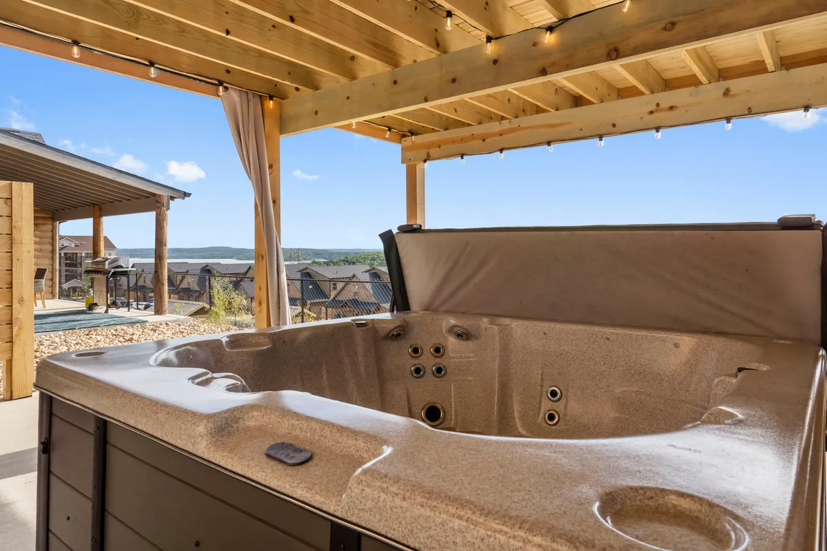 This image showcases a private hot tub under a wooden pergola, set against a backdrop of mountains. The setting exudes tranquility and offers a perfect spot for friends to unwind together while enjoying nature and starry skies.